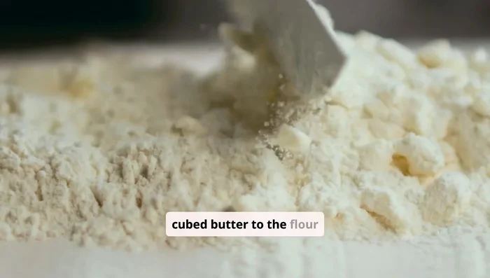 Add cold cubed butter to the flour mixture. Use your fingers or a pastry cutter to work the butter into the flour until you have pea-sized pieces. Some larger chunks are okay.