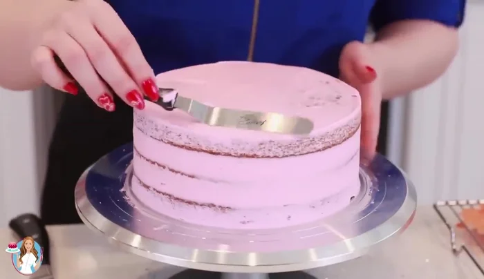 Apply the final layer of frosting. Decorate with fresh red roses.