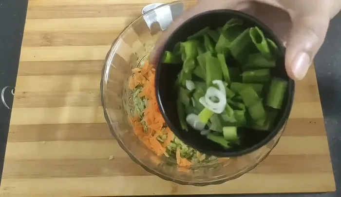 Add spring onions and green chilies to the squeezed zucchini.