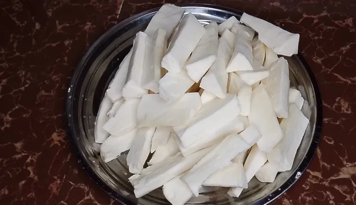 In a pan, combine cassava with garlic powder, salt, and turmeric. Add a little water to prevent burning and allow the spices to infuse into the cassava.