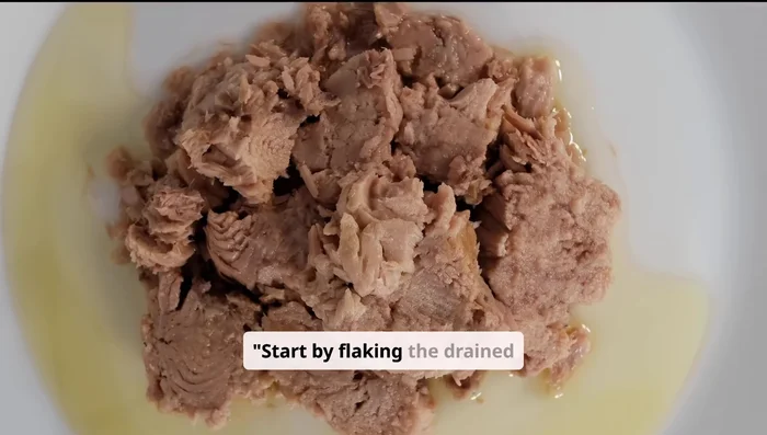 Flake the drained tuna into a mixing bowl.