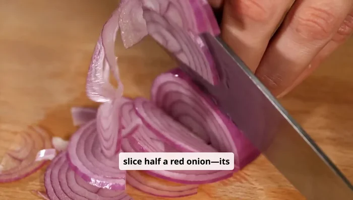 Thinly slice half a red onion and add to the bowl.
